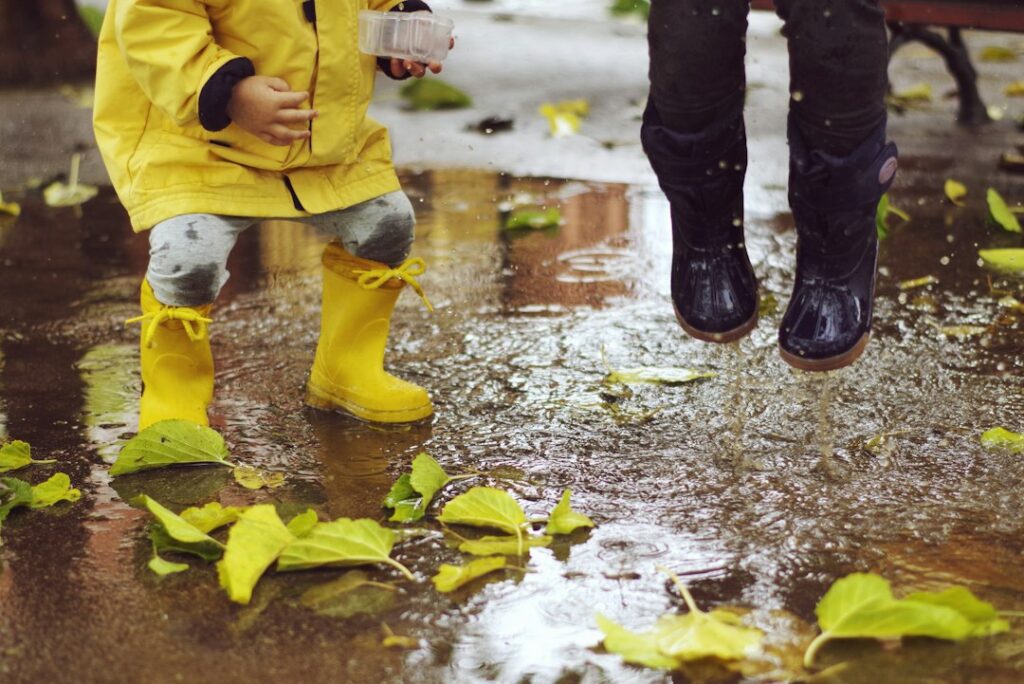 Tout-petit en ciré jaune et bottes de pluie dans une flaque d’automne